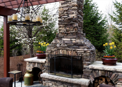 Outdoor living space with fireplace, pergola, and lighting.