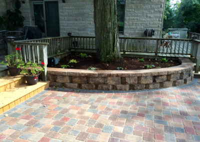 Paver patio with raised stone wall flower bed.
