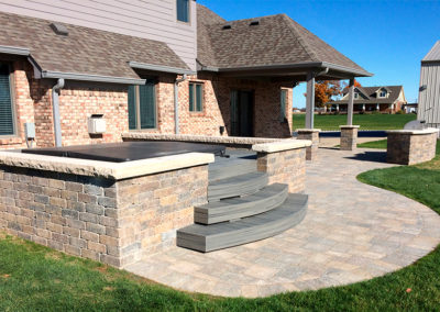 Paver patio with hot tub enclosure and built-in grill.