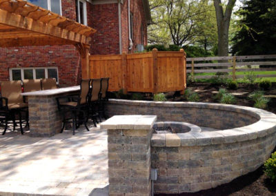 Paver patio with pergola, bar, fire pit and sitting wall.