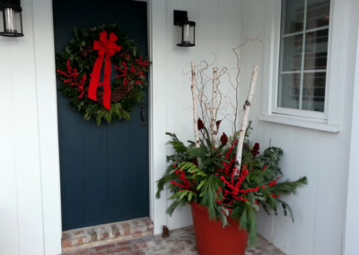 Front porch with winder container and fresh green wreath.